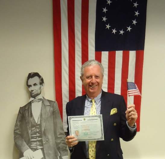 Stuart Kennedy holding up his Citizenship and American flag